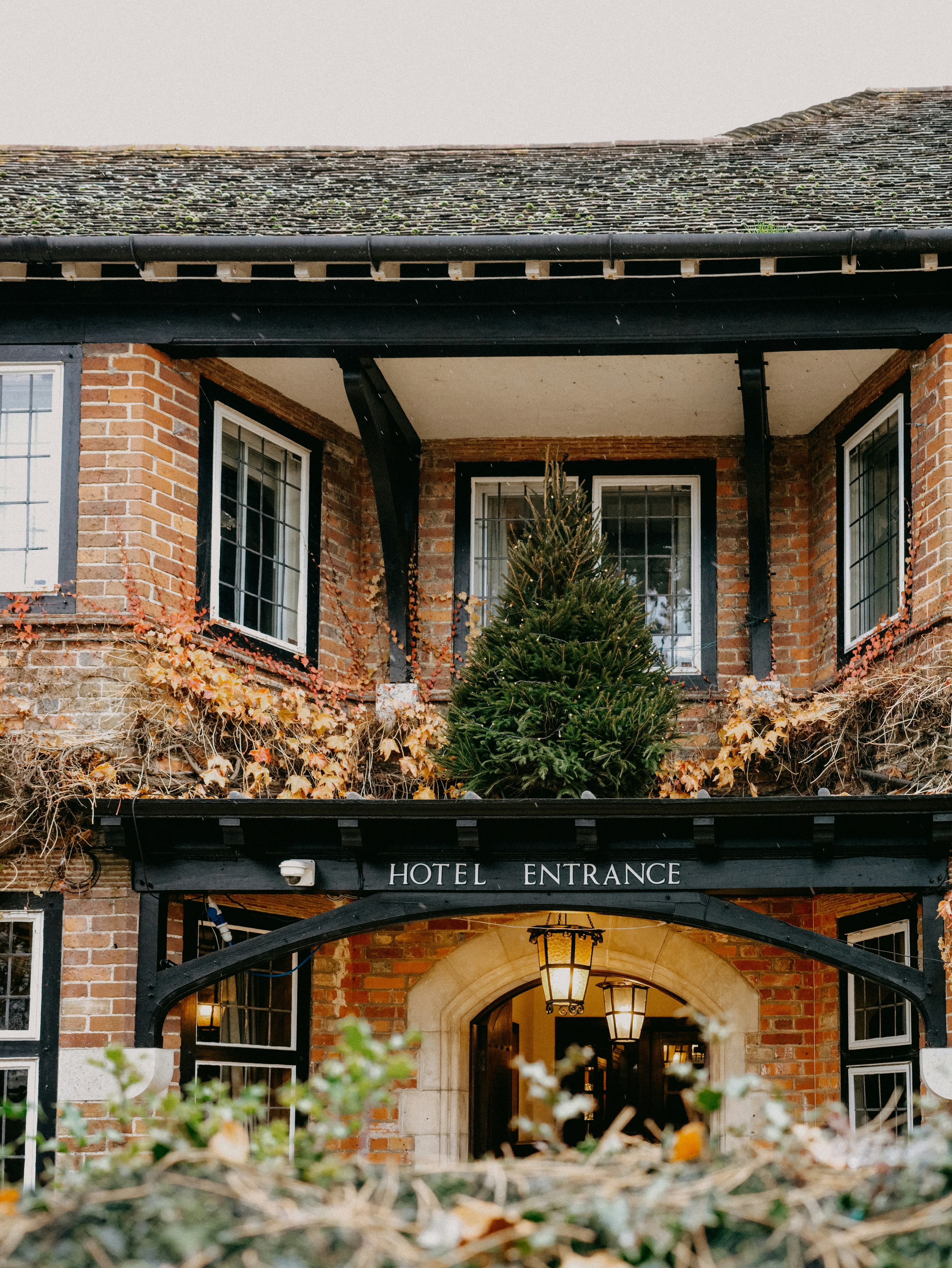 Brick and timber hotel entrance with lanterns and a Christmas tree