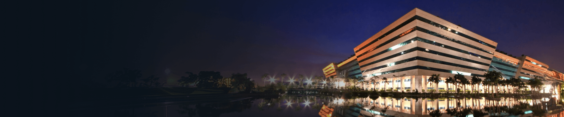 Hotel building exterior lit up at night with a reflecting pool